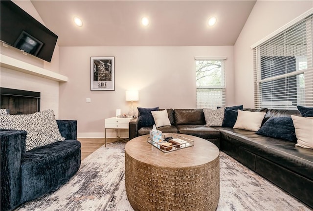 living area with baseboards, lofted ceiling, wood finished floors, a fireplace, and recessed lighting