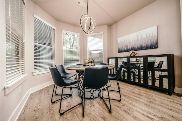 dining space with a chandelier, wood finished floors, visible vents, and baseboards