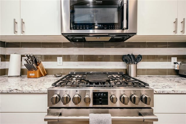 kitchen with light stone countertops, appliances with stainless steel finishes, white cabinets, and decorative backsplash