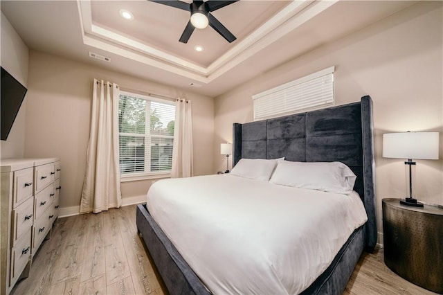 bedroom with light wood-style flooring, recessed lighting, visible vents, baseboards, and a tray ceiling