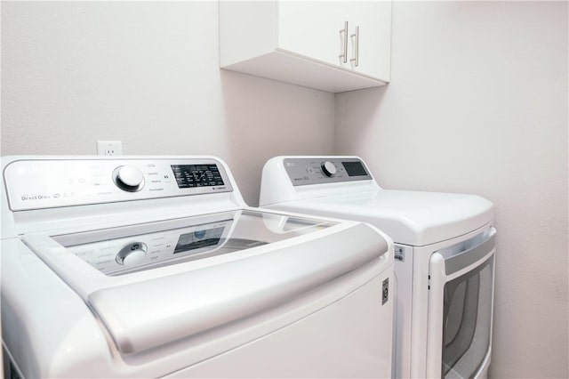 clothes washing area featuring washer and clothes dryer and cabinet space