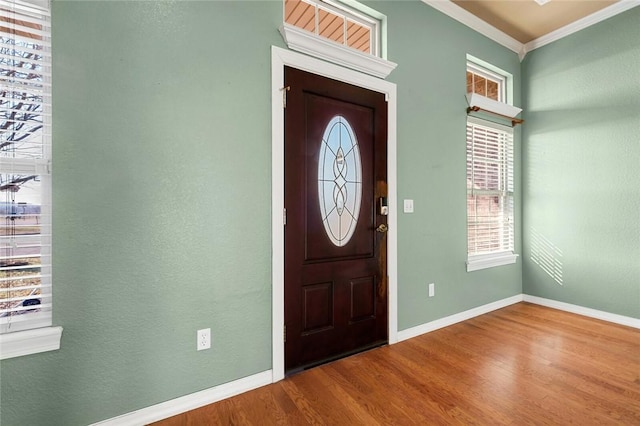 entryway featuring baseboards, ornamental molding, and wood finished floors