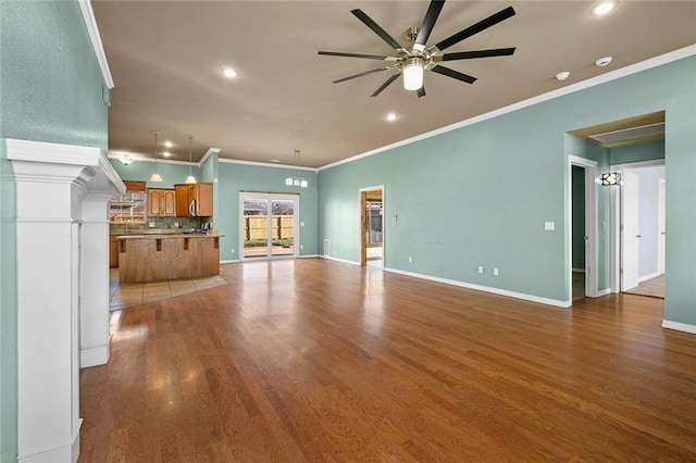 unfurnished living room with ceiling fan, crown molding, baseboards, and wood finished floors