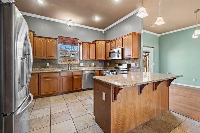 kitchen with a breakfast bar area, a peninsula, a sink, appliances with stainless steel finishes, and brown cabinets