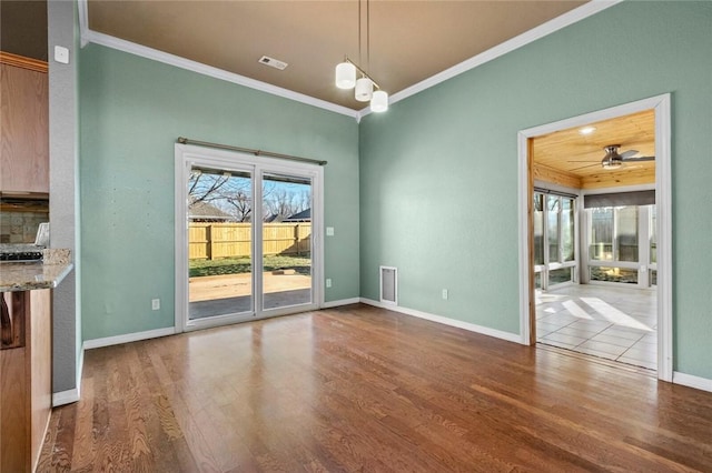 unfurnished dining area featuring a ceiling fan, crown molding, baseboards, and wood finished floors