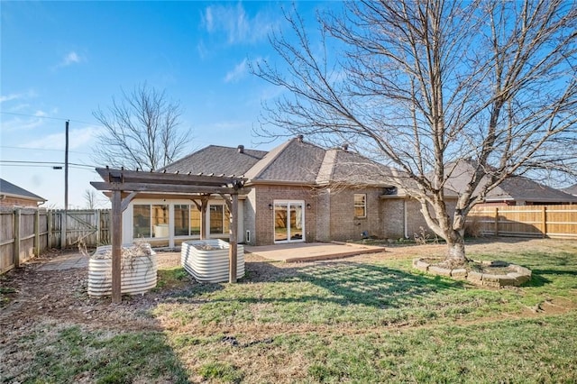 rear view of house featuring brick siding, a fenced backyard, a patio, and a yard