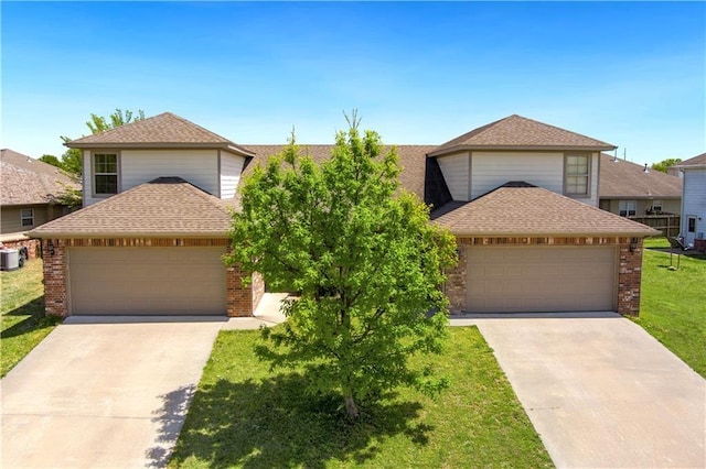 traditional-style home featuring a garage, brick siding, driveway, roof with shingles, and a front lawn