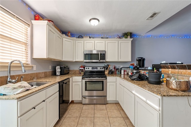 kitchen with visible vents, appliances with stainless steel finishes, white cabinetry, a sink, and light tile patterned flooring