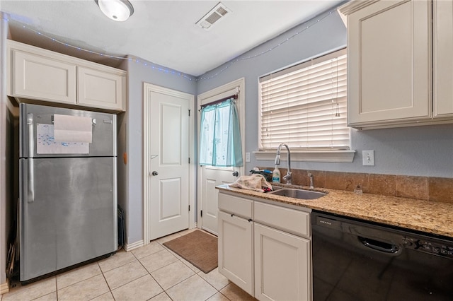 kitchen featuring light tile patterned floors, a sink, visible vents, freestanding refrigerator, and dishwasher