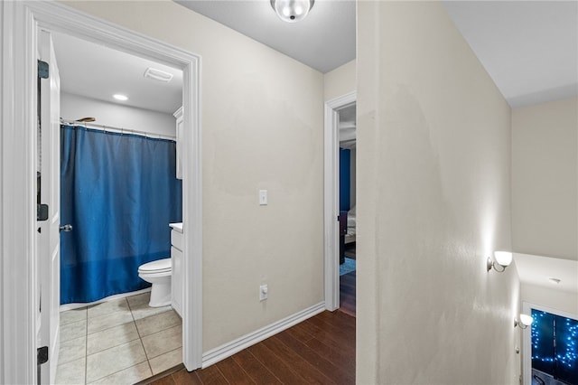 bathroom featuring curtained shower, wood finished floors, toilet, and baseboards