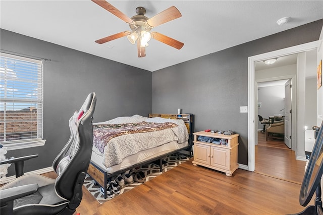 bedroom featuring a ceiling fan, baseboards, and wood finished floors