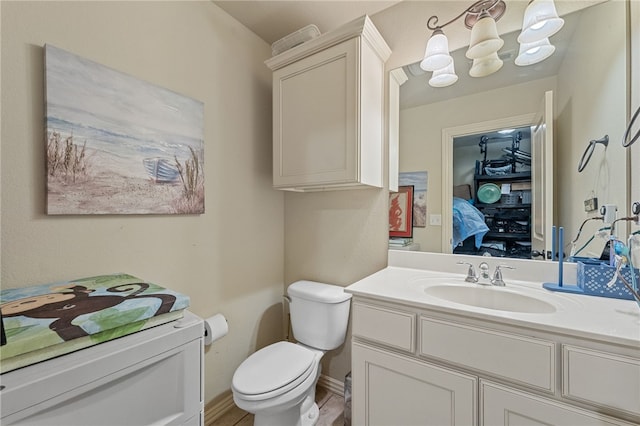 ensuite bathroom featuring baseboards, toilet, ensuite bath, an inviting chandelier, and vanity