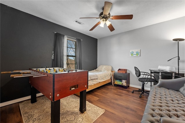 bedroom featuring a ceiling fan, visible vents, baseboards, and wood finished floors