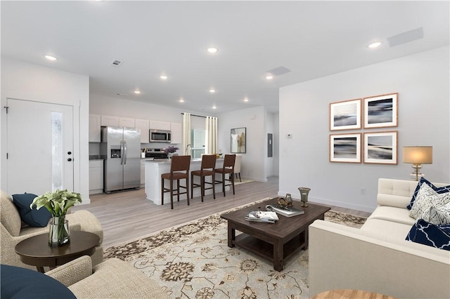 living area with light wood-type flooring and recessed lighting