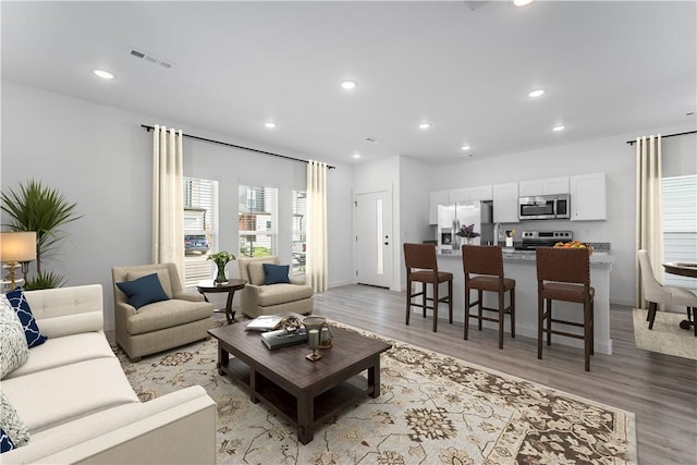 living area with recessed lighting, visible vents, and light wood-style flooring