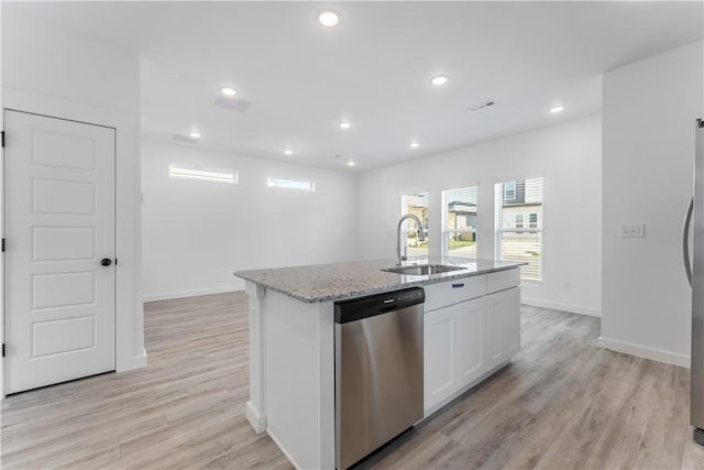 kitchen featuring white cabinets, light stone countertops, stainless steel appliances, light wood-style floors, and a sink