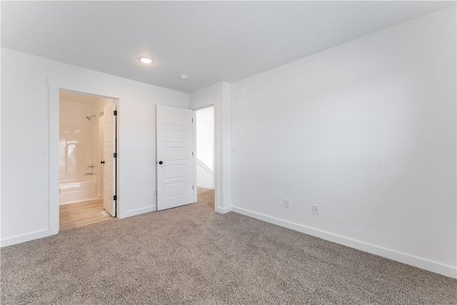 unfurnished bedroom featuring carpet flooring, ensuite bath, and baseboards