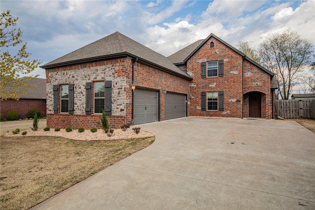 view of front facade with concrete driveway, brick siding, a shingled roof, and fence