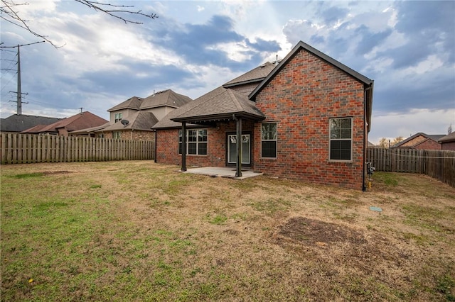 back of property featuring a yard, brick siding, a patio area, and a fenced backyard