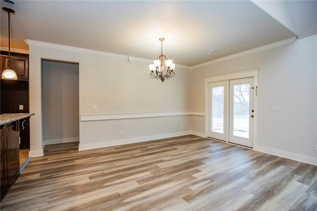 unfurnished dining area featuring light wood-type flooring, crown molding, and baseboards