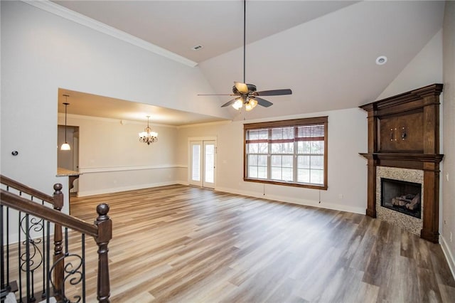 unfurnished living room with crown molding, stairway, a large fireplace, vaulted ceiling, and wood finished floors