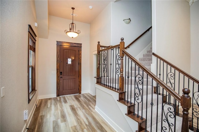 foyer with stairs, baseboards, a high ceiling, and wood finished floors