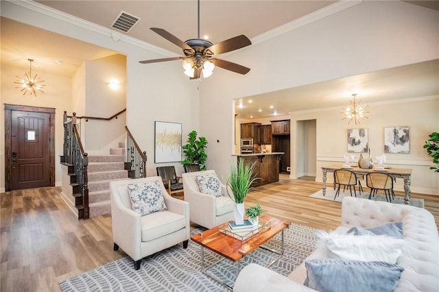 3601 SW Willowbrook Rd, Bentonville, AR 72713 - living area with crown molding, stairs, ceiling fan with notable chandelier, light wood-style flooring, and visible vents