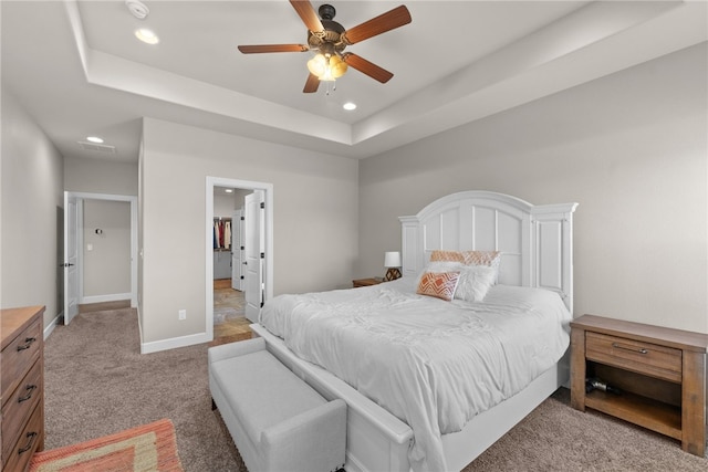 bedroom featuring light carpet, baseboards, a ceiling fan, a tray ceiling, and recessed lighting