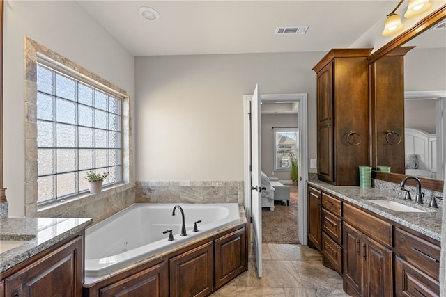 ensuite bathroom featuring a sink, a wealth of natural light, visible vents, and connected bathroom