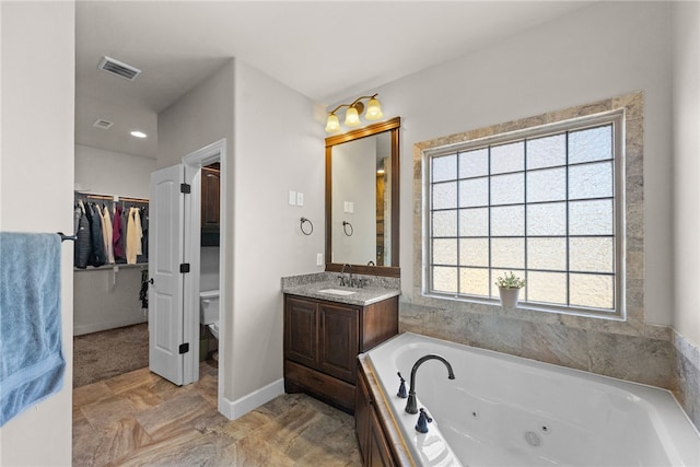 bathroom featuring a wealth of natural light, visible vents, vanity, and a whirlpool tub