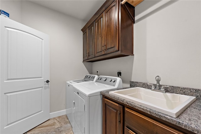 laundry area featuring cabinet space, baseboards, washer and dryer, and a sink