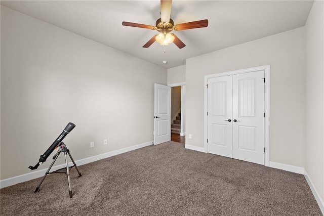 interior space with carpet floors, a closet, ceiling fan, and baseboards