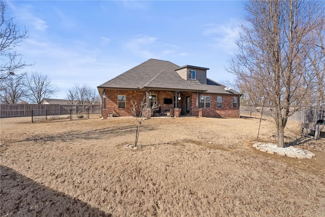 view of front of property featuring brick siding, a shingled roof, and fence