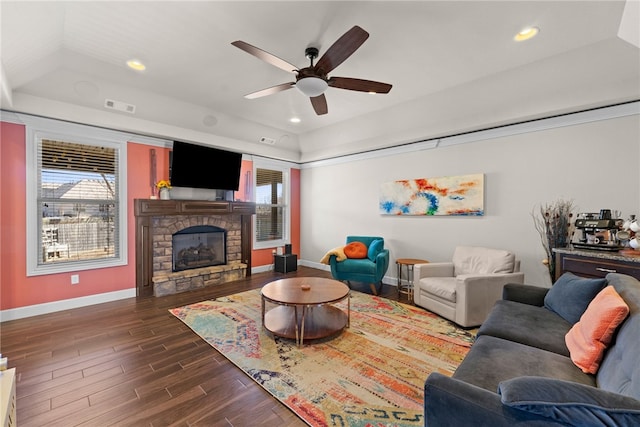 living room featuring a tray ceiling, dark wood-type flooring, visible vents, and a healthy amount of sunlight