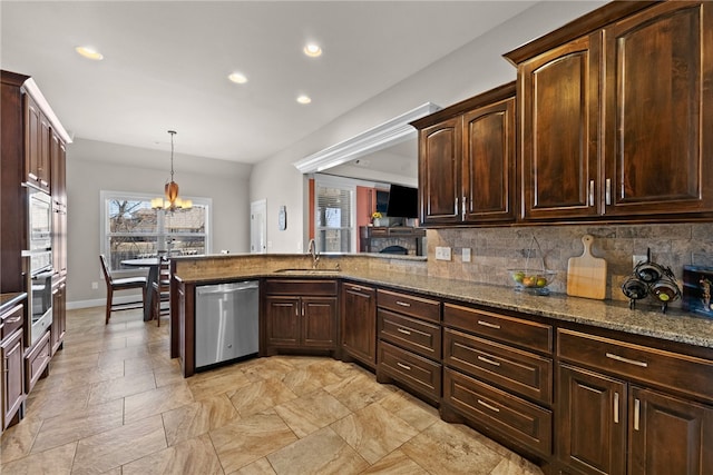 kitchen with stainless steel appliances, stone counters, a sink, and decorative backsplash