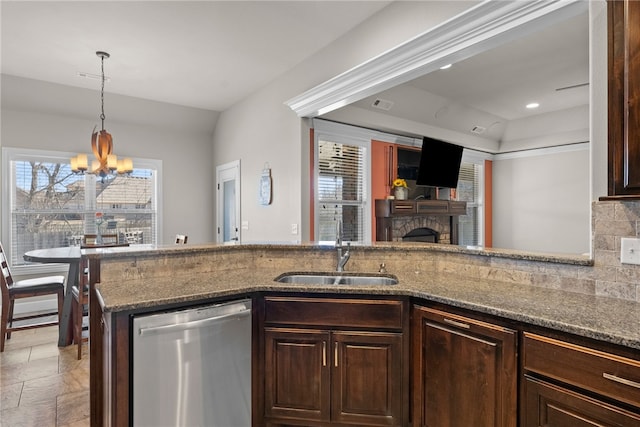 kitchen with tasteful backsplash, dark stone countertops, dark brown cabinets, stainless steel dishwasher, and a sink