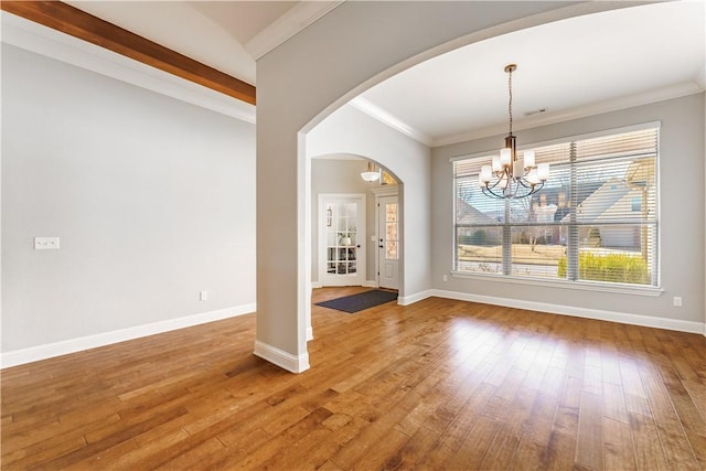 unfurnished dining area with arched walkways, wood-type flooring, and baseboards