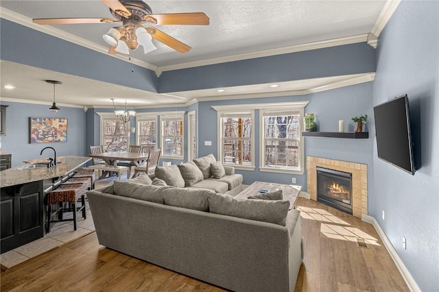 living area featuring a fireplace, baseboards, crown molding, and light wood-style floors