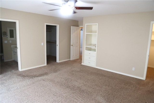 unfurnished bedroom with carpet, a spacious closet, baseboards, and a closet