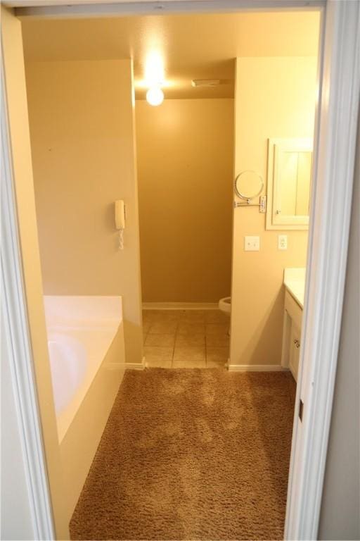 full bathroom with tile patterned flooring, toilet, vanity, baseboards, and a bath