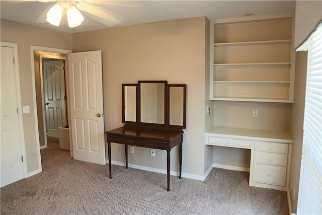 unfurnished bedroom with light carpet, built in desk, and baseboards