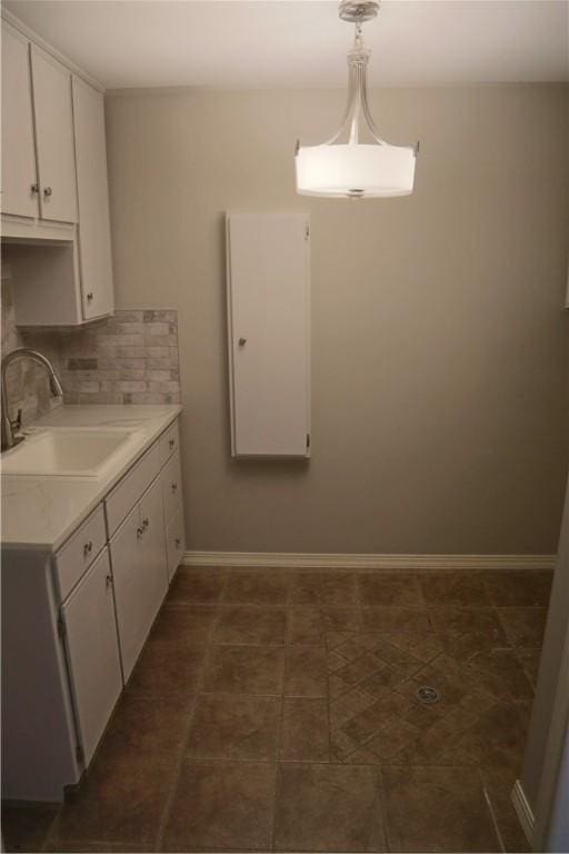 kitchen featuring light countertops, white cabinetry, a sink, and backsplash