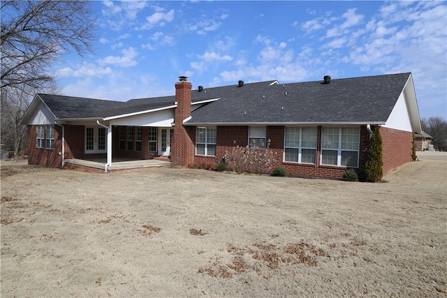 rear view of property featuring a shingled roof, french doors, brick siding, and a chimney