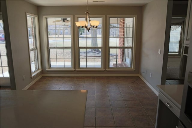 unfurnished dining area with a chandelier, dark tile patterned floors, and baseboards