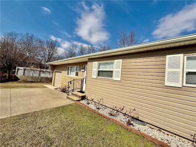 view of front of home featuring an attached garage, fence, a front yard, driveway, and a patio area