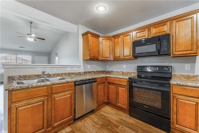 kitchen featuring black appliances, light wood finished floors, a sink, and brown cabinets