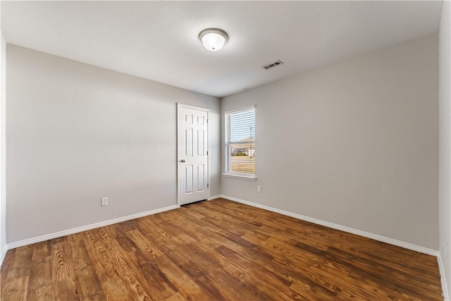 spare room with visible vents, baseboards, and wood finished floors