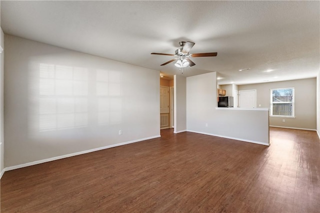 spare room with a ceiling fan, visible vents, baseboards, and dark wood-type flooring