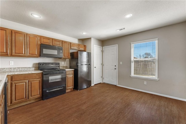 kitchen featuring brown cabinets, light countertops, dark wood-type flooring, black appliances, and baseboards