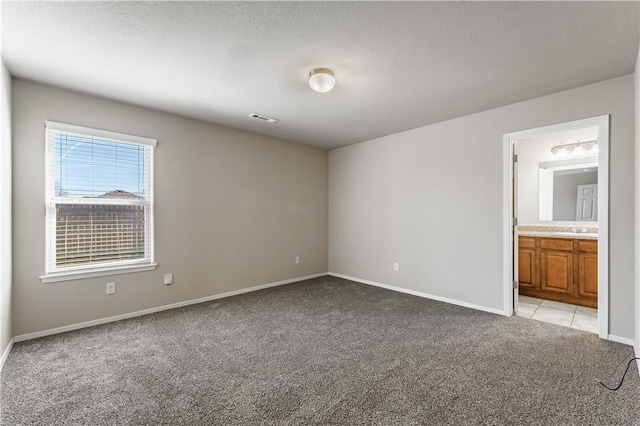 interior space featuring visible vents, light carpet, a sink, a textured ceiling, and baseboards